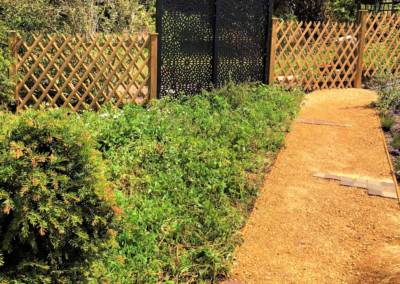 Traditional meets contemporary with these two differing boundary materials. A wildflower meadow to the left, which includes a plum tree, borders a breedon gravel path leading around the garden
