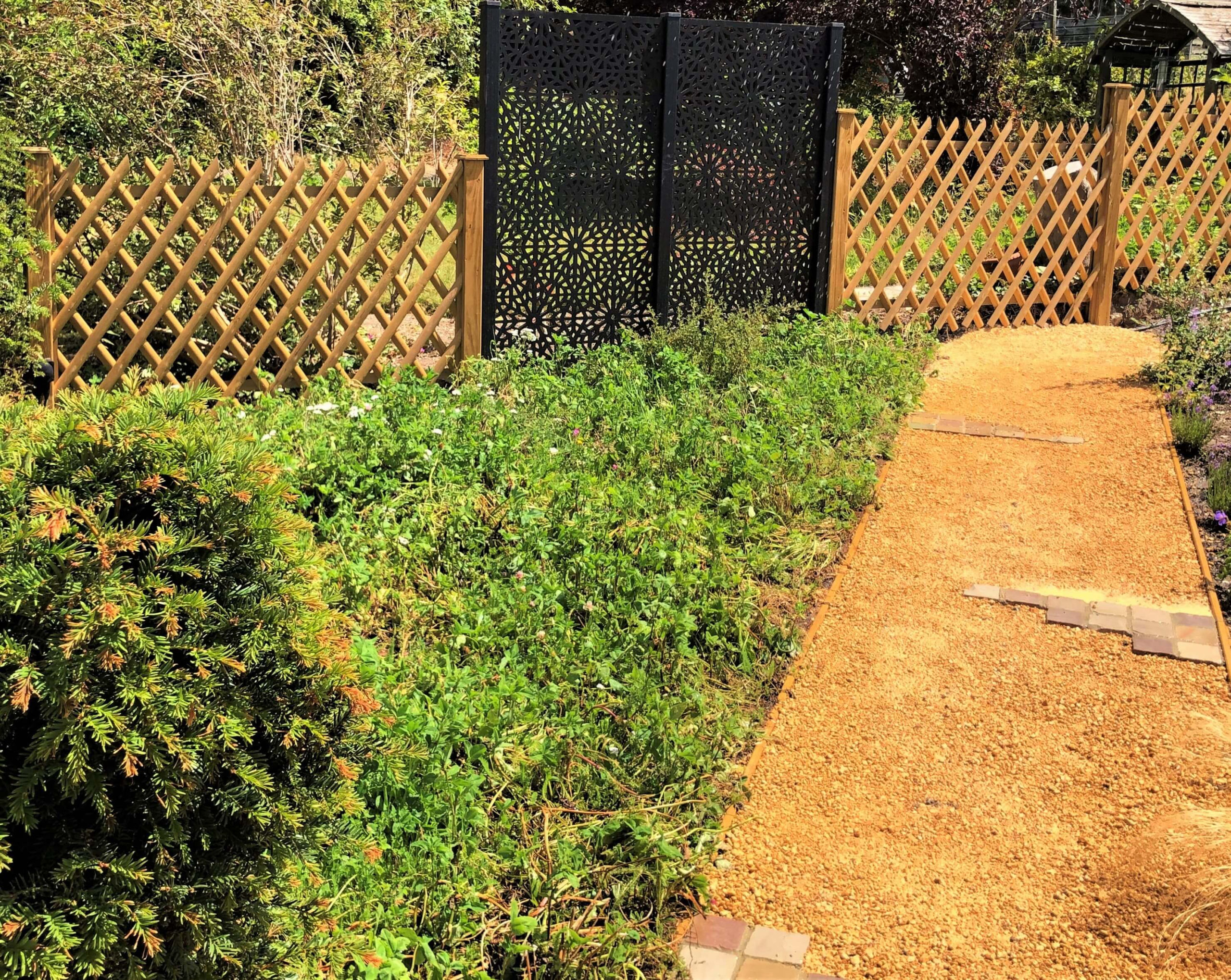 Traditional meets contemporary with these two differing boundary materials. A wildflower meadow to the left, which includes a plum tree, borders a breedon gravel path leading around the garden
