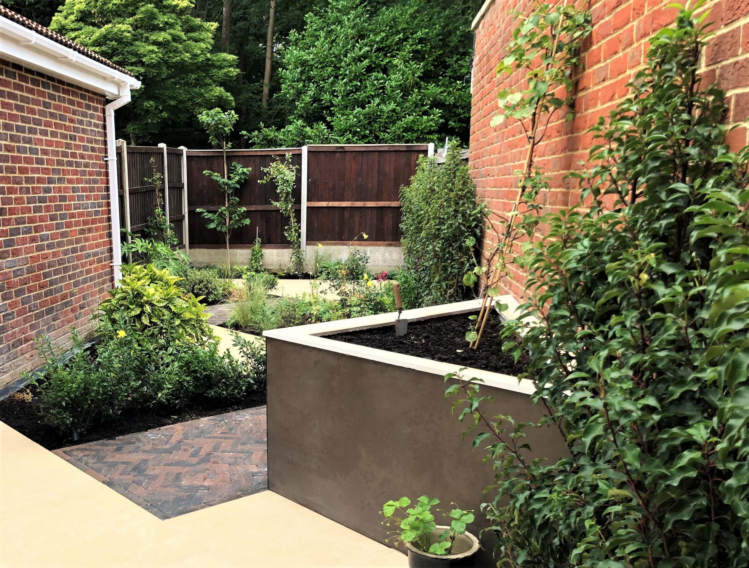 Diagonal layout and Mocha-clad raised bed in a Meopham garden Garden design in Meopham, Kent - diagonal layout with Jura Beige porcelain, Mocha-clad raised bed and mixed evergreen planting