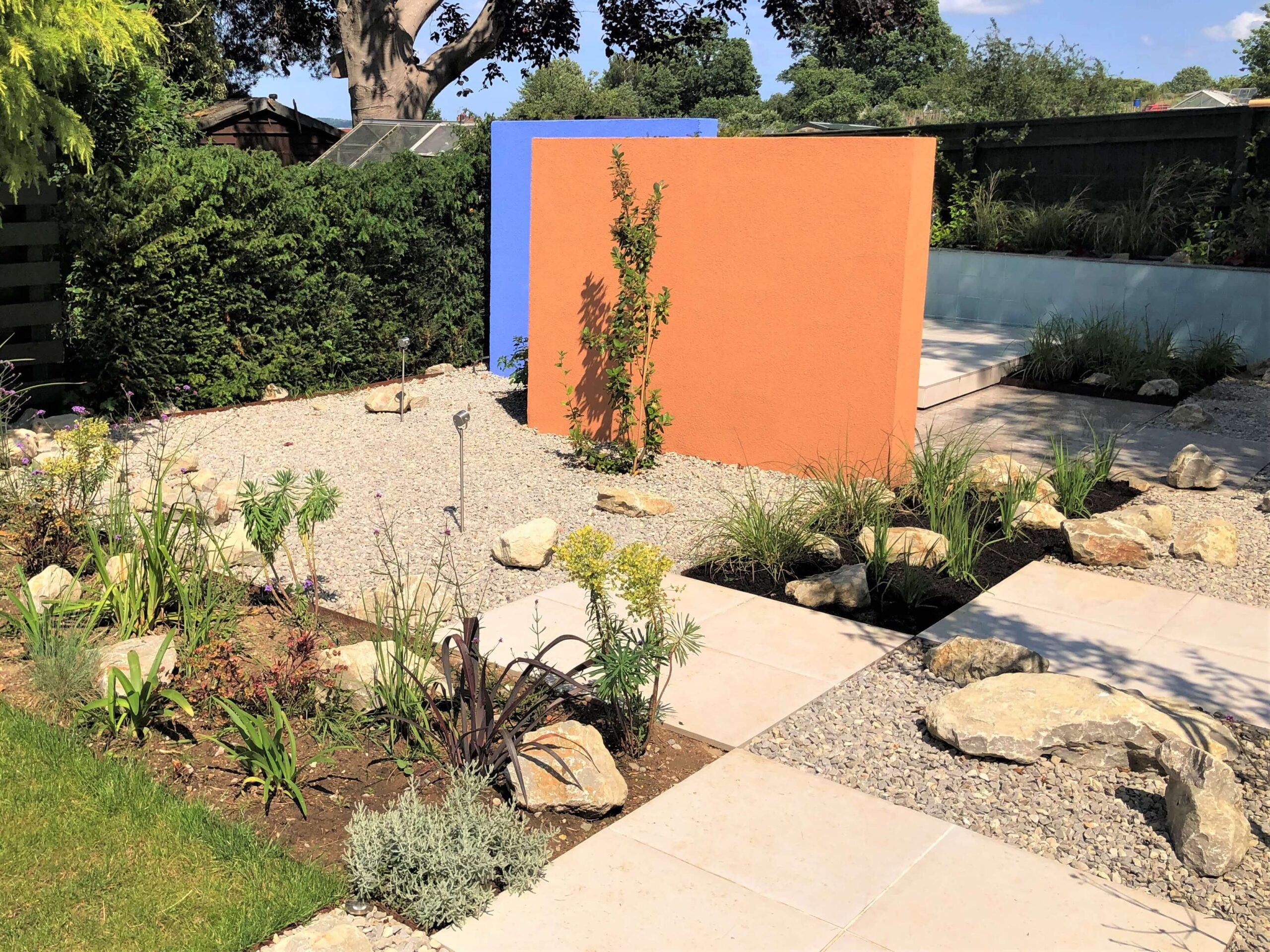 Desert modernism in Sevenoaks Colourful walls acting as blank canvases, abundant planting, large boulders and beautiful paving.