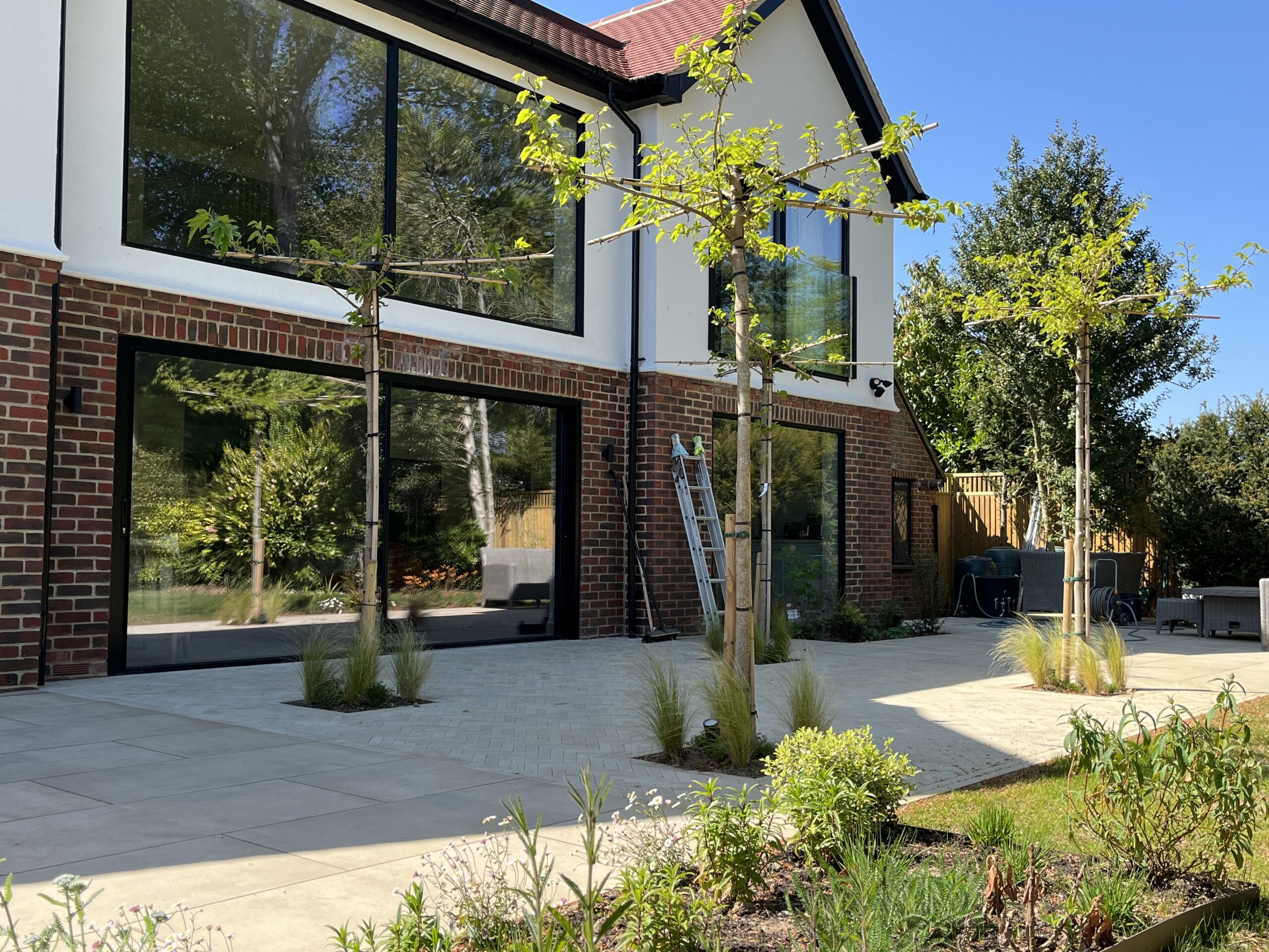 Parasol trees offer shade during a late morning coffee and break up the herringbone sandstone paving