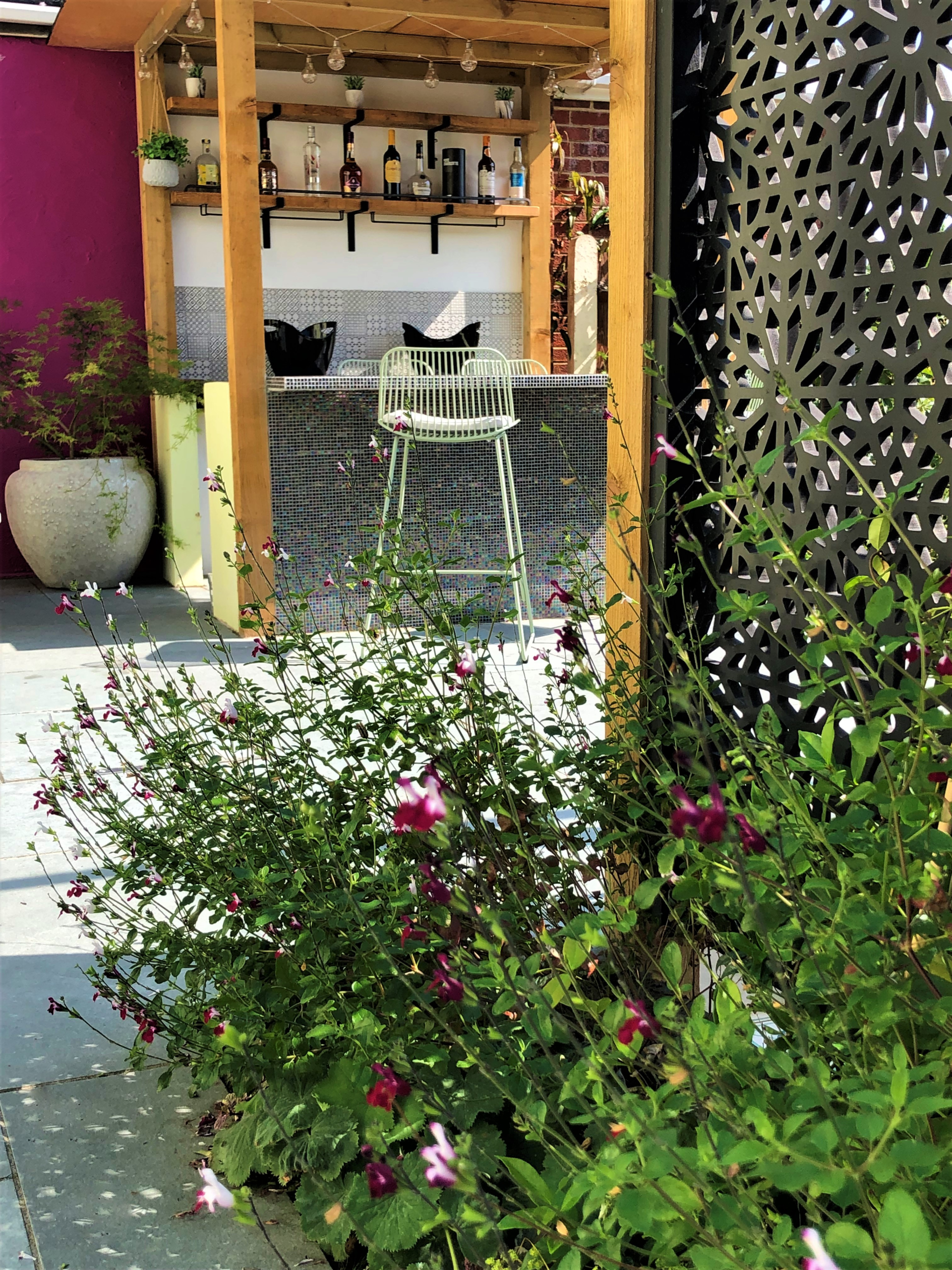 The bar and Moucharabiya screen in a Bexley garden Bexley garden bar seen through Salvia planting, with mosaic-tiled front and Moucharabiya screen