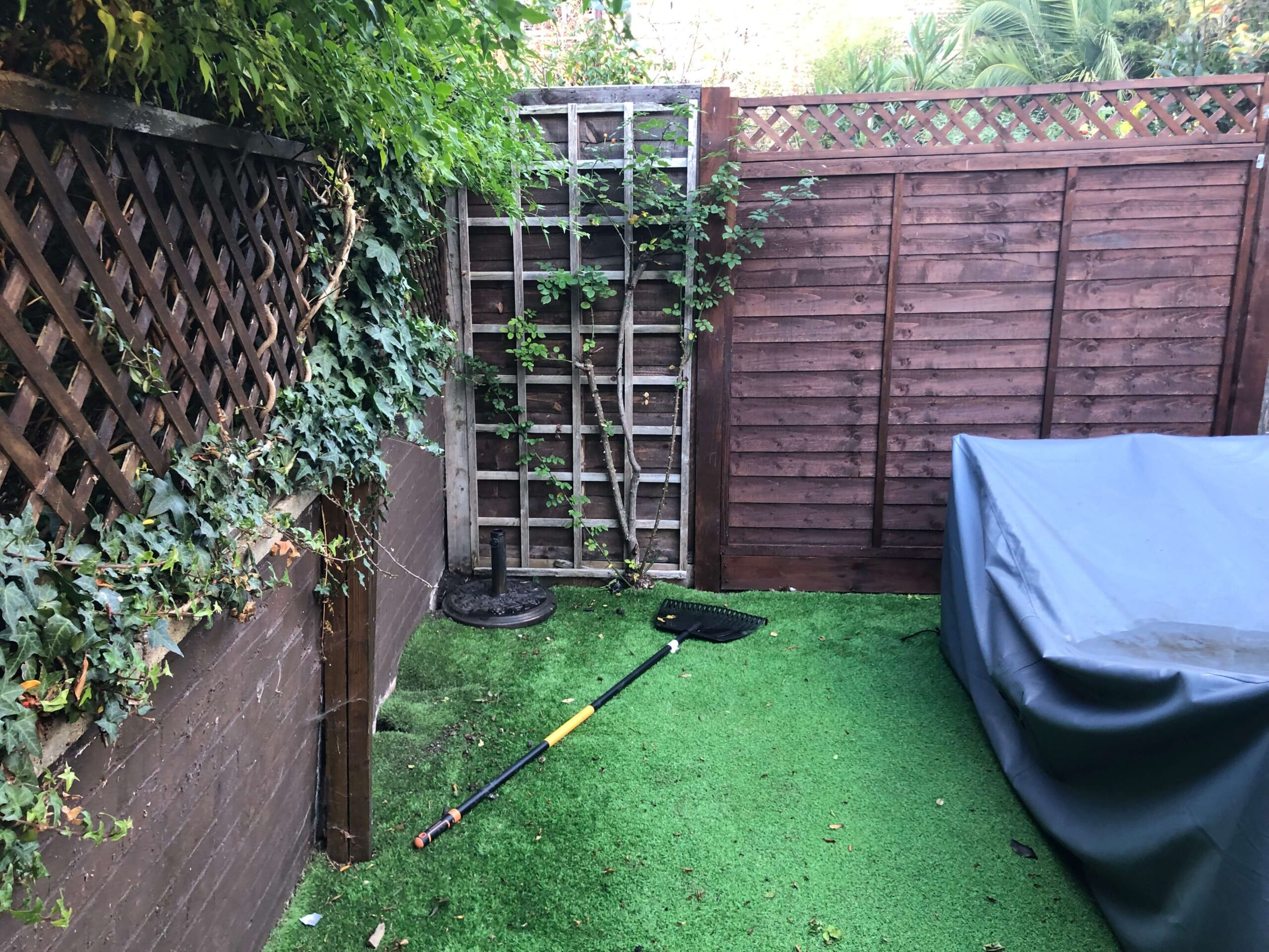 Before the transformation - the leaning rear wall Before - Camberwell garden with the leaning rear wall, dark fencing and worn artificial grass prior to redesign
