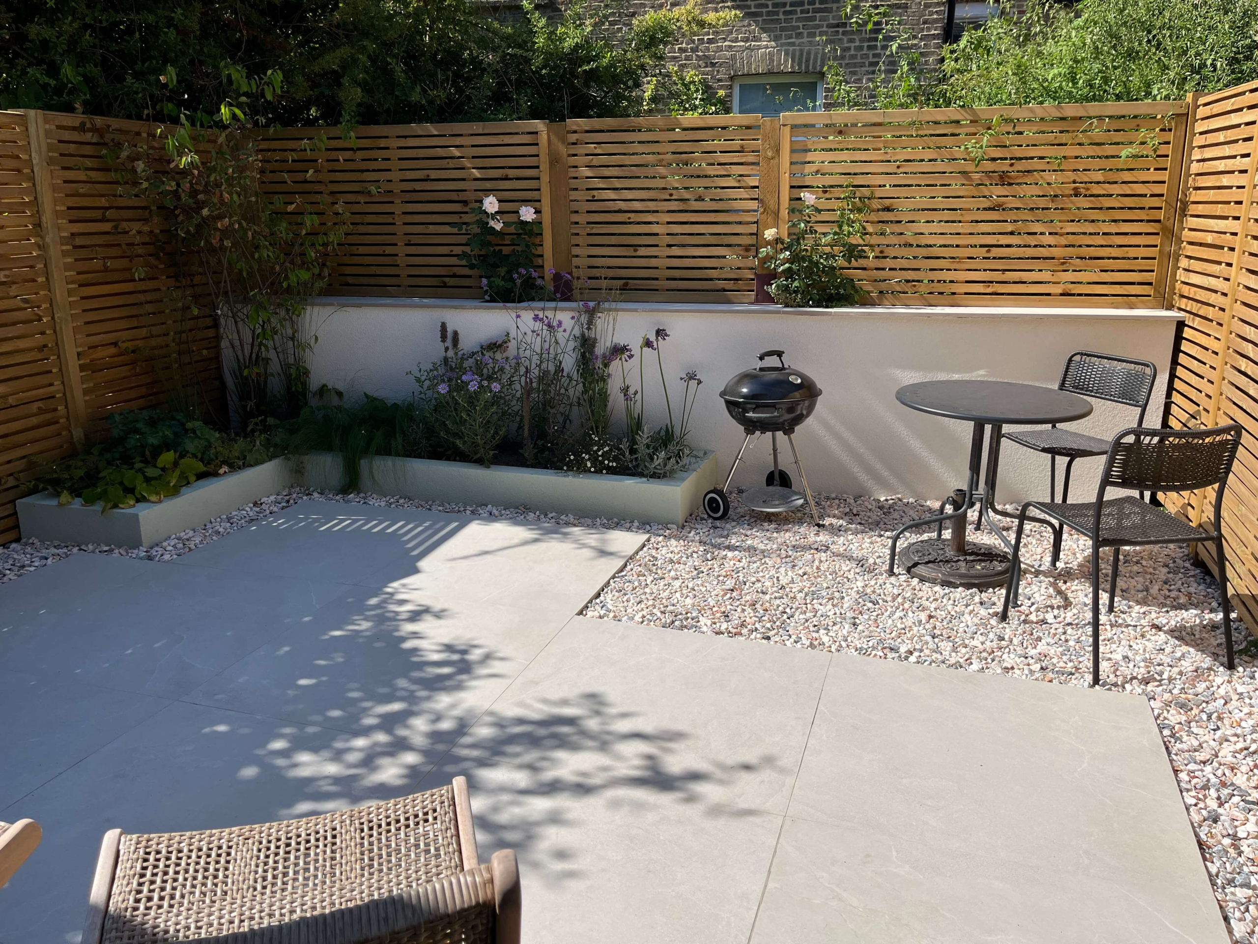 Finished modern courtyard garden in Camberwell Modern garden design in Camberwell, south London - white porcelain patio, batten screening and mixed sun and shade planting