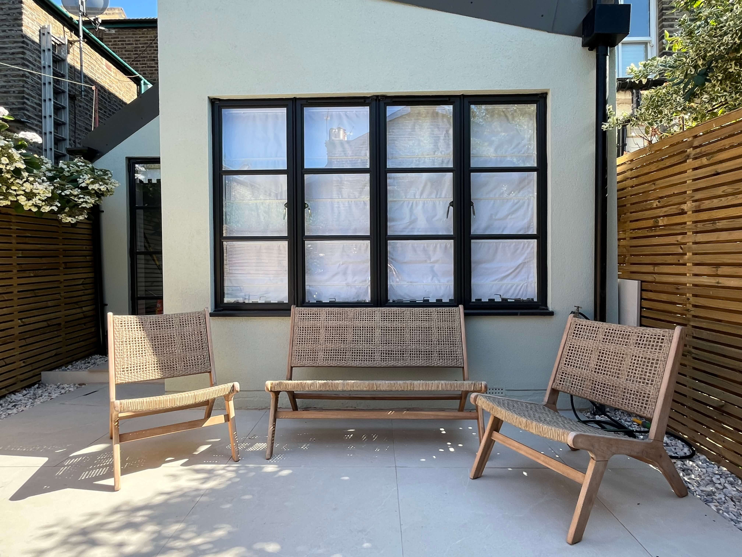 Private seating area in a Camberwell garden Alt text:<br />
Modern garden design in Camberwell south London - private seating area with sage green extension and batten screening